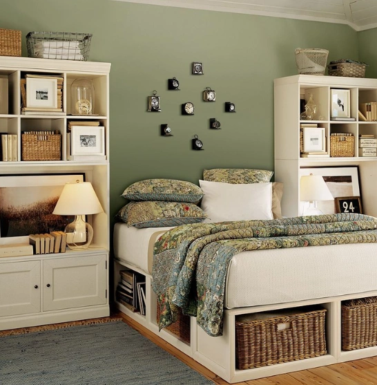 A cozy bedroom features ample storage, bookshelves on both sides of the bed, and small clocks mounted on the wall.