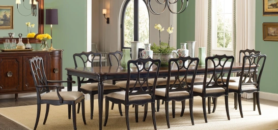 formal dining room with a large rectangular table, cushioned chairs, soft green walls on art & plants.
