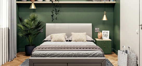 A modern green bedroom features a large bed, lighting, a drawer, frame & a Kentia palm on the left side.