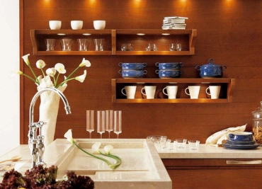 A stylish kitchen counter with flowers and neatly arranged shelves with dishware with calm Lighting.