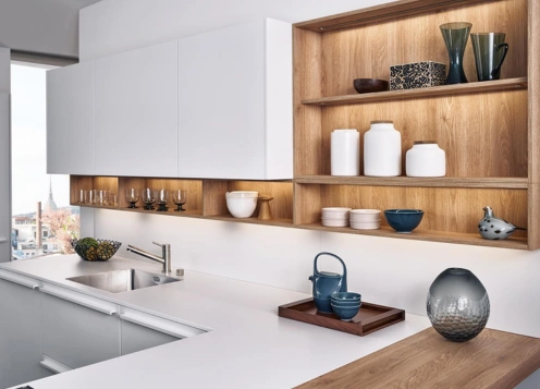 A sleek modern kitchen featuring pristine white cabinets, stylish wooden shelves, and decorative utensils.