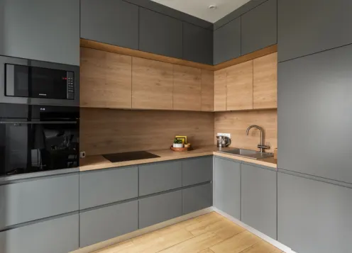 Modern U-shaped kitchen with deep blue cabinets, gray countertops, breakfast bar, oven, & shelving unit.
