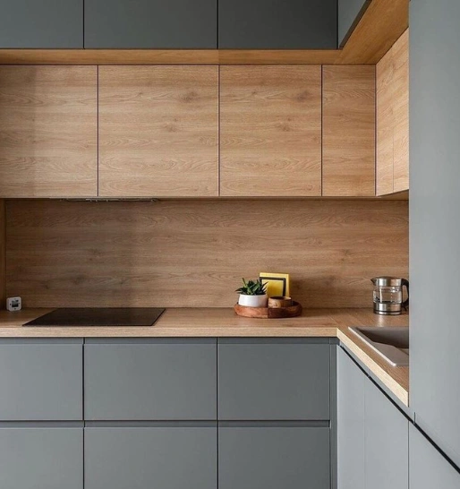 Modern kitchen with gray cabinets, wood-paneled upper cabinet & a countertop with a wooden cutting board.