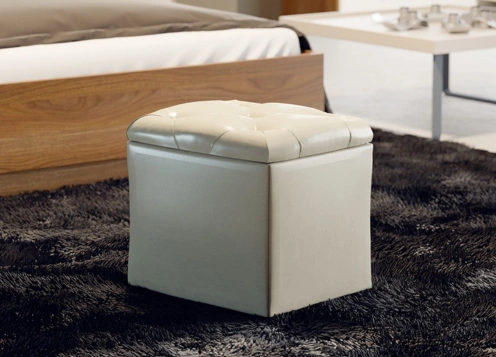 A white ottoman placed on a neatly made bed, adding a touch of elegance to the bedroom decor.