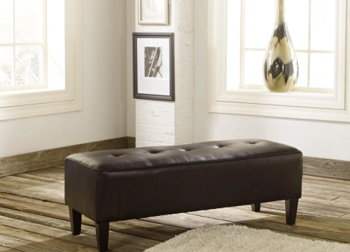 A white ottoman is placed on a neatly made bed, adding a touch of elegance to the bedroom decor.