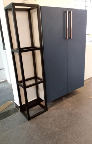 A lack shelving unit stands elegantly next to a spacious blue cabinet, accented with metal handles.