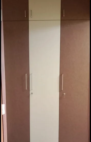 A wardrobe featuring brown and white doors, accented with modern metal handles for a stylish touch