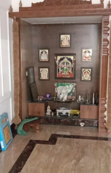 A home altar with religious icons, statues, and ceremonial items enclosed in a wooden arch.