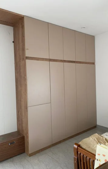 A spacious wooden wardrobe stands tall against a pristine wall, with a glimpse of a cozy crib nearby.