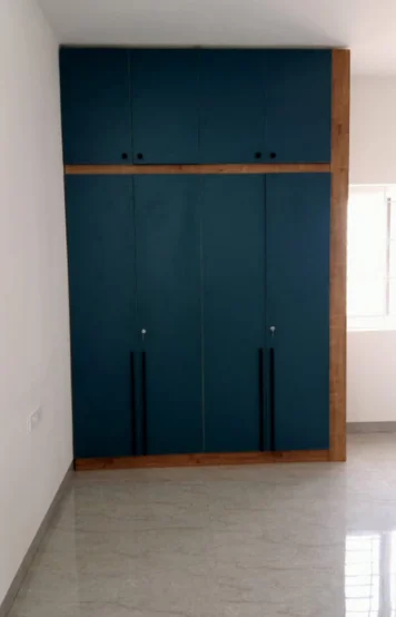 A wardrobe with black handles stands out beautifully in a room with crisp white walls & marble flooring.