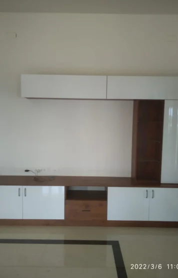A modern kitchen interior with white and wooden cabinets, and a bare wall ready for appliances.