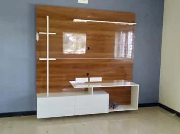 A modern wooden entertainment TV unit with white accents against a gray wall with amazing light