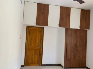 A spacious, empty room featuring a rustic wooden door, flanked on both sides by cabinets, adding warmth.