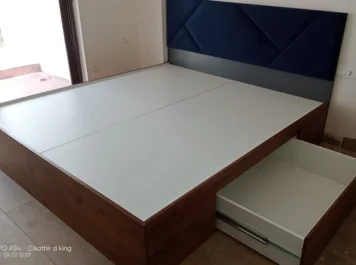 A bed frame featuring an open storage drawer & a chic blue headboard, perfect for any modern bedroom.