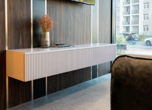 Modern floating console table against a wood-paneled wall in a minimalist room with a window View.