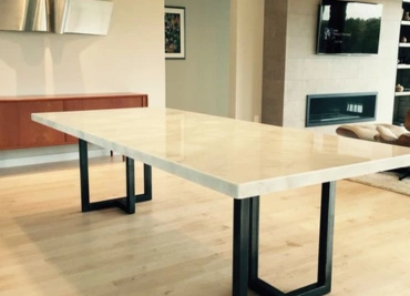A sleek, modern marble table sits gracefully in a minimalist room with warm hardwood floors beneath
