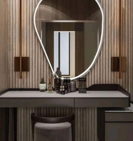 A dressing table with a large irregularly shaped mirror, marble countertop drawers & stylish wall sconces.