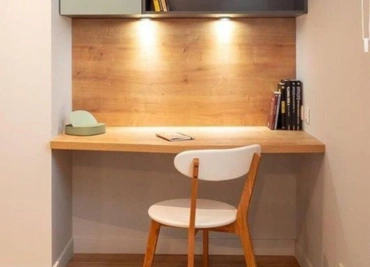 Modern minimalist study area with wooden desk, chair, and wall-mounted shelves with decorative items.