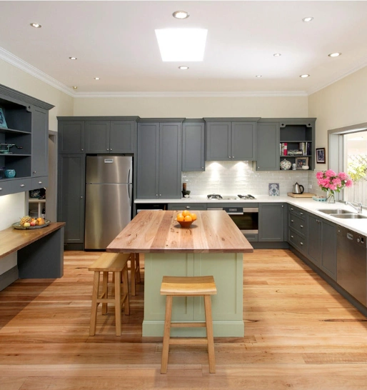 Spacious kitchen with gray cabinets, a wooden breakfast bar with stools, a skylight & a refrigerator