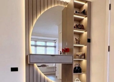 An entryway with a wooden wall, a circular mirror, and built-in shelves to hold bags and decor accessories. write correct formate 