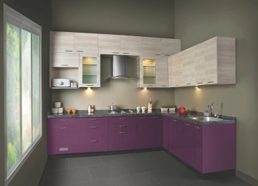 Modern L-shaped kitchen with purple cabinets chimney hood, dark countertop under lighting, & large window.