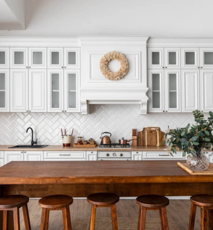 Modern kitchen with white cabinets and wooden stools, designed by a top interior designer for style.
