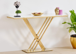 Modern console table with a gold X-shaped base, marble top, decorative objects, and a plant beside it.