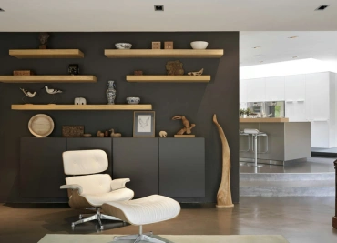 A well-designed living room with custom wall shelves and a chair highlights modern decor and space.