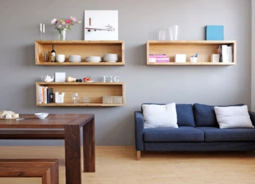 The living room features gray walls, three floating shelves, a blue sofa, and a wooden Tea table.